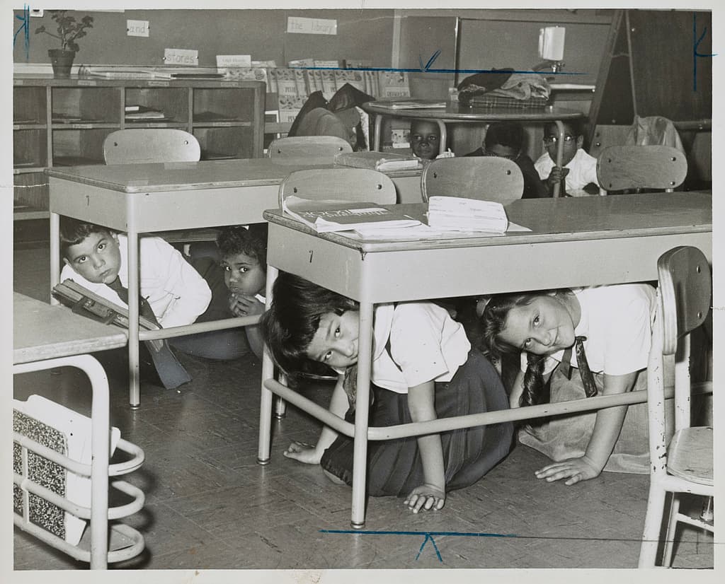 Duck and cover school drill showing students taking protective posture after a simulated flash