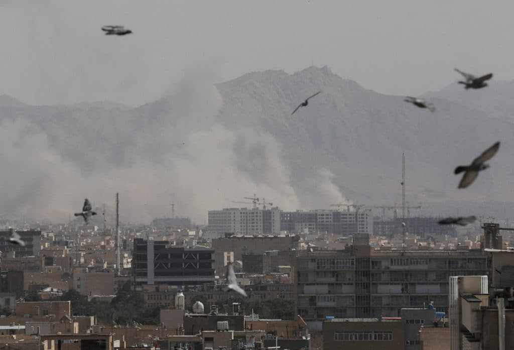 Smoke rising over Tehran skyline as seen from a rooftop with birds in flight following U.S.-Israeli airstrikes during Operation Epic Fury, March 2026